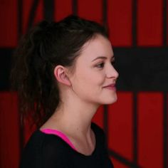 a woman standing in front of a red wall with black bars on it's sides