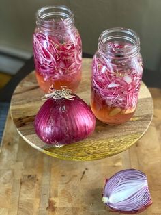 two jars filled with red onions on top of a wooden table