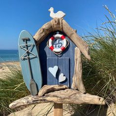 a birdhouse made out of driftwood with a life preserver and surfboard