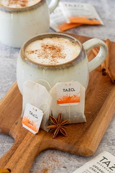 two mugs of hot chocolate with cinnamon sprinkles on a cutting board