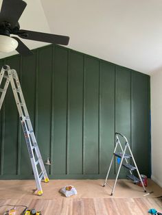 two ladders are in the middle of a room with green walls and wood flooring