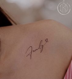 the back of a woman's shoulder with a small tattoo on it that says family