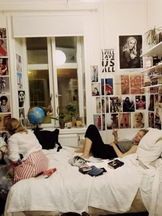 two people laying on a bed in a room with many pictures all over the wall