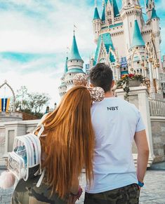 a man and woman standing in front of a castle with their backs to each other