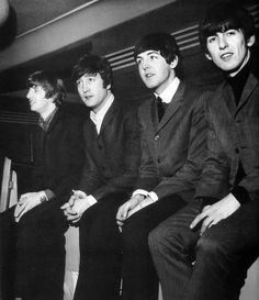 the beatles are sitting down in suits and ties