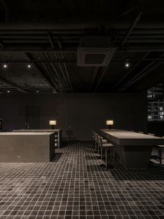 an empty room with tables and stools in the center, lights on above them