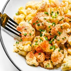 a white plate topped with cauliflower covered in seasoning next to a fork