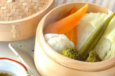 there are vegetables in the wooden bowl on the table next to chopsticks and sauce