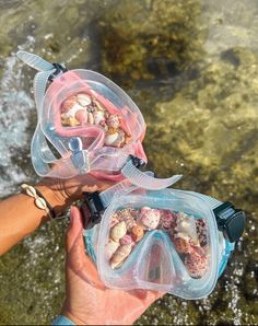 someone is holding two snorkels in front of the water and some sea shells