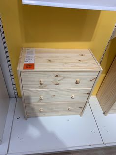 a wooden dresser sitting next to a yellow wall