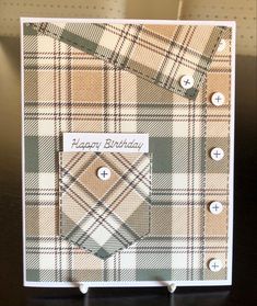 a birthday card with buttons on it and some plaid fabric in the background, sitting on a table