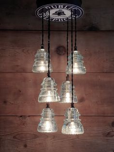 a chandelier made out of glass hanging from a wooden wall with lights on it