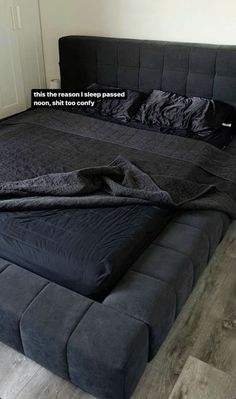 a bed that has a black blanket on top of it with a quote above the headboard