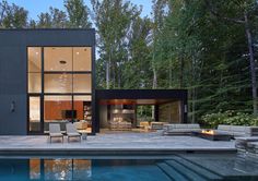 a modern house with a pool in the foreground and outdoor furniture on the other side