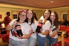 four girls in white shirts holding up bottles