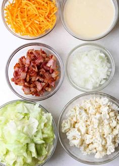 four bowls with different types of food in them on a white counter top next to cheese, carrots and lettuce