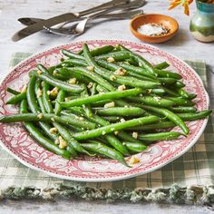 a plate with green beans on it next to some utensils and spoons