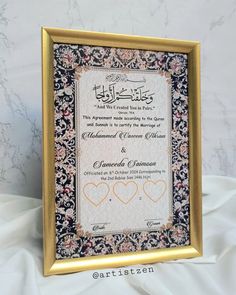 an ornate frame with two hearts in the middle and arabic writing on it, sitting on a white sheet