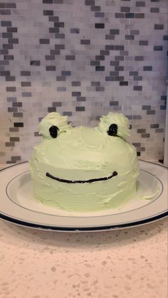 a white cake with green frosting and a smiling face on it's side