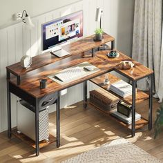 a desk with a computer on it in front of a white wall and wooden floor