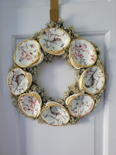 a wreath is hanging on the door with four plates in it and moss growing all around