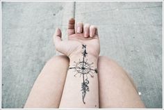 a black and white photo of someones arm with a compass tattoo on it