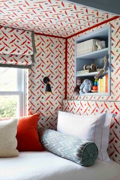 a bedroom with red, white and blue wallpaper on the walls next to a window