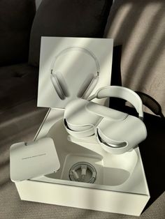 an open box with headphones in it sitting on a couch next to a pillow