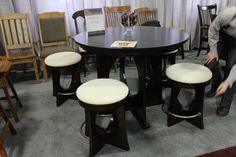 a table with four stools in front of it and a man standing next to it