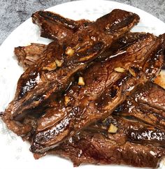 some steaks on a white plate covered in sauce