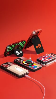 an assortment of cell phones and accessories on a red surface with the phone plugged in