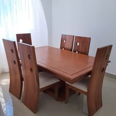 a wooden table with six chairs around it in a room that has white walls and tile flooring