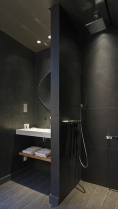 a modern bathroom with black walls and wood flooring on the shower head is shown