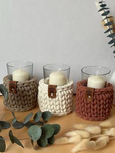 three crocheted baskets with candles in them on a table