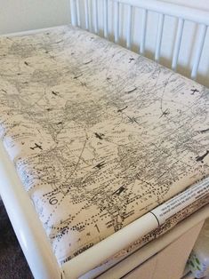 a white crib with an old world map on the top and bottom sheet that has been turned into a changing table