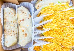 two burritos and some shredded cheese in a box