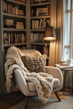 a chair with a blanket on top of it in front of a bookshelf