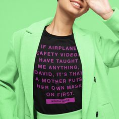 a woman wearing a green jacket and black t - shirt with the words if airplane safety video have taught me anything, it's that a mother puts her own mask on first