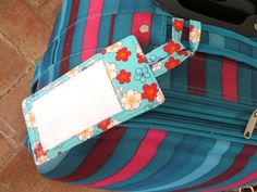 a piece of luggage sitting on top of a tile floor next to a bag tag