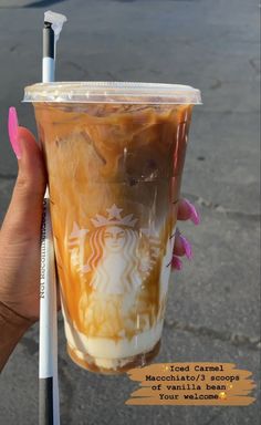 a hand holding up a cup with liquid in it and a straw sticking out of the top