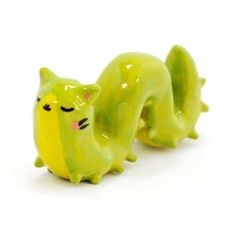 two green ceramic cats sitting next to each other on a white surface and one has its eyes closed