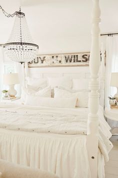 a white bed sitting under a chandelier in a bedroom