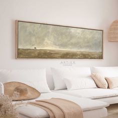 a living room with a large painting on the wall and white couches in front of it