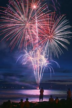 people watching fireworks on the beach at night