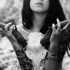 a woman with horns and tattoos holding her hands up