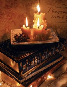 three lit candles sitting on top of books