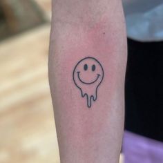 a small smiley face tattoo on the arm