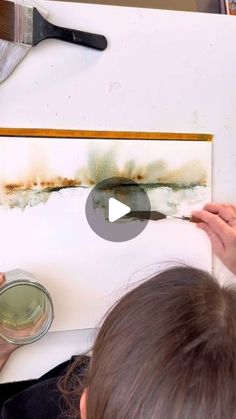 a woman is painting on the wall with brown paint