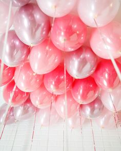 a bunch of pink and white balloons hanging from the ceiling