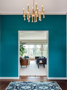 an open door leading to a living room with blue walls and wood floors, chandelier hanging from the ceiling